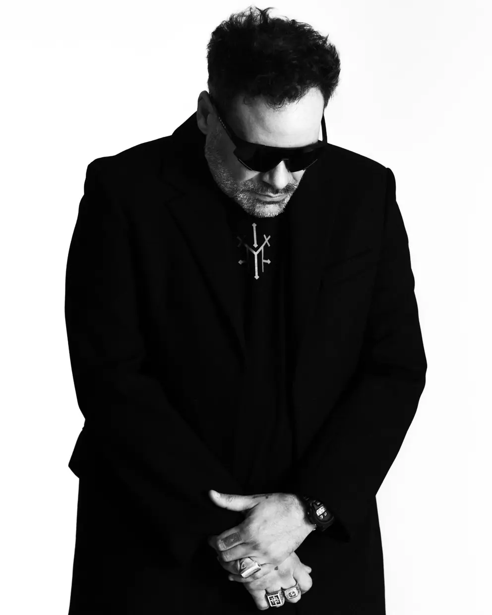 Black-and-white portrait in a dark coat, head bowed